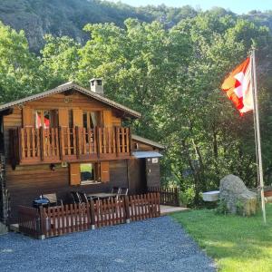 una cabaña de madera con una bandera delante de ella en Le Passage en Salvan