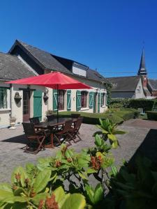 a picnic table with a red umbrella in front of a building at La Clé des Champs in Longueval