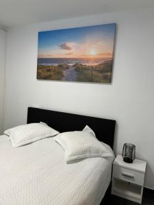ein Schlafzimmer mit einem weißen Bett und einem Gemälde an der Wand in der Unterkunft Appartement Justine in Blankenberge