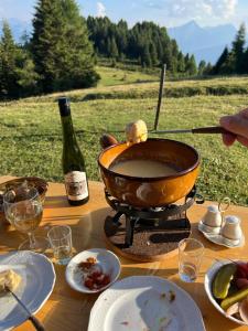 un tavolo con una padella di cibo e una bottiglia di vino di Alp Jurte Skihütte Feldis a Feldis