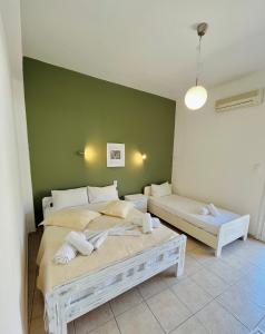 um quarto com 2 camas e uma parede verde em Diana Studios em Pefki