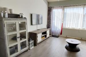 een woonkamer met een tv en een kruk erin bij Beach Appartement 17 - Callantsoog in Callantsoog