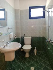 a green tiled bathroom with a toilet and a sink at Vila Rosen in Lozenets