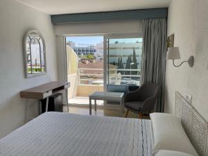 ein Hotelzimmer mit einem Bett, einem Schreibtisch und einem Fenster in der Unterkunft Hostal Roberto in Palmanova