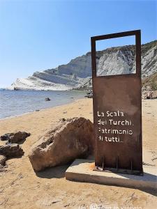 a sign on a beach with a rock at Villa Maresa Home in Realmonte