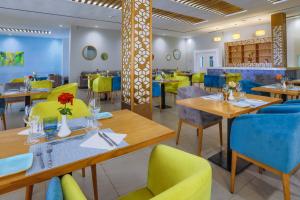 un restaurant avec des tables en bois et des chaises colorées dans l'établissement Be Live Collection Saïdia, à Saïdia