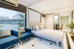 a bedroom with a bed and two blue chairs at VietHOME Trang Tien in Hanoi