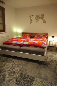 ein Schlafzimmer mit einem Bett mit einer orangen und roten Decke in der Unterkunft Hotel Kirchbühl in Schönau im Schwarzwald