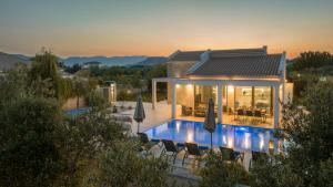 a villa with a swimming pool in front of a house at Zante Prime Villas in Gaïtánion