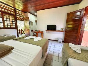 a hotel room with two beds and a television at Eco Pousada Paraíso dos Coqueirais in Japaratinga