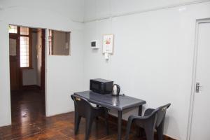 a room with a table with a microwave and chairs at Gielex Guest House in Durban