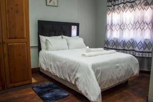 ein Schlafzimmer mit einem großen Bett mit weißer Bettwäsche und Kissen in der Unterkunft Gielex Guest House in Durban