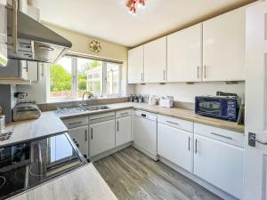 a kitchen with white cabinets and a counter top at Buxton Holiday Home in Buxton