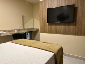 um quarto de hotel com uma cama e uma televisão de ecrã plano em Hotel Planaltina em Planaltina