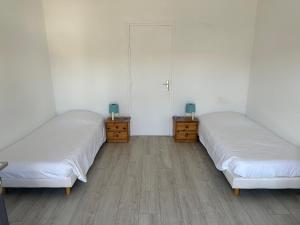 PleybenにあるLes chambres du Bistro du Canalの白い壁とウッドフロアの客室で、ベッド2台が備わります。