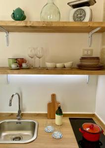 a kitchen counter with a sink and glasses on a shelf at Casa Portacrànni in San Pietro in Bevagna