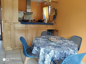 a dining room table with blue chairs and a kitchen at Gîte de Porspol in Brignogan-Plages