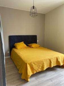 sypialnia z łóżkiem z żółtą pościelą i lampką w obiekcie Maison 5 chambres 3sdb en ville avec piscine w mieście Périgueux
