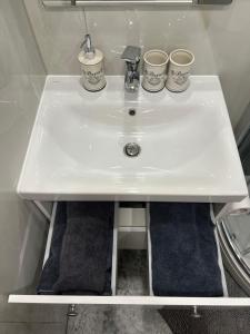 a white sink with three cups on top of it at Stradinya apartment in Ventspils