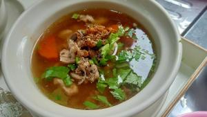 a bowl of chicken noodle soup with meat and cilantro at Rangyen Homestay Cha-Am รังเย็น in Cha Am