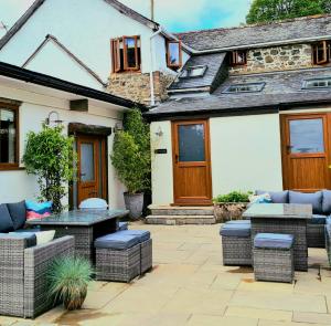 a patio with wicker furniture in front of a house at Historic Property with Stunning Views (Walk to the pub) in Hennock