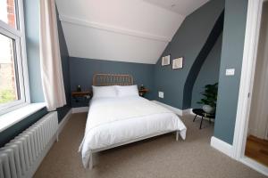a bedroom with a white bed and blue walls at The Artist's House in Scarborough