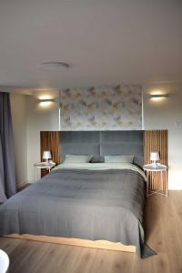 a bedroom with a large bed and two tables at Bursztynek in Stegna