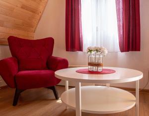 ein Wohnzimmer mit einem roten Stuhl und einem Tisch in der Unterkunft Casa Del Durmitor in Žabljak