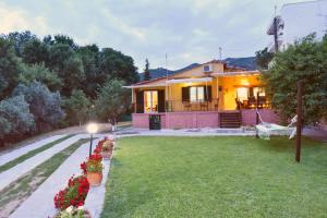 a house with a yard with flowers in front of it at Xenophon House in Paleo Tsifliki