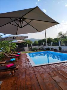 a pool with chairs and umbrellas on a wooden deck at Apartment Karla SNB in Lozovac