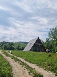 a barn with a dirt road in front of it at Cabana lu’ Ilie in Şinca Nouă