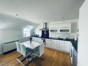 a kitchen with white cabinets and a table and chairs at Ballina Town Centre Duplex Apartment in Ballina