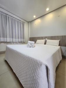 1 dormitorio con 1 cama blanca grande y toallas. en Oiti Hotel - By Up Hotel en Gurupi