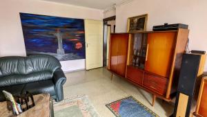 a living room with a leather chair and a dresser at Große Ferienwohnung mit Loggia und Garten in Cottbus (direkt am Klinikum) in Cottbus