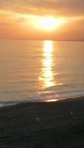 a sunset on the beach with the sun setting over the water at Apartamento primera linea de Playa. Wifi in Retamar