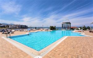 a large swimming pool next to a beach with a building at DOME Hotel & Casino at Central Kyrenia in Kyrenia
