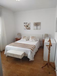 a white bedroom with a bed and two pictures on the wall at Pension Fercomar in Sanxenxo