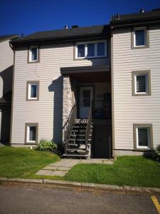 une maison avec un escalier menant à la porte d'entrée. dans l'établissement Les Condos de la Montagne 1, à Beaupré