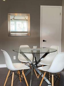 a glass table and white chairs in a room at Les Condos de la Montagne 1 in Beaupré