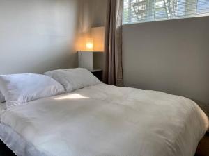 1 cama blanca en un dormitorio con ventana en Les Condos de la Montagne 1 en Beaupré