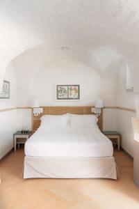 a bedroom with a large white bed with two tables at Masseria Auraterrae in Polignano a Mare