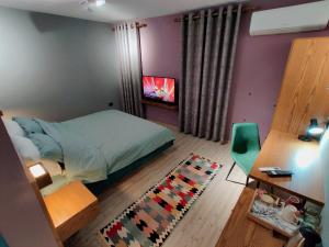 Schlafzimmer mit einem Bett, einem Tisch und einem TV in der Unterkunft Piro's Cozy Rooms - City Centre in Korçë