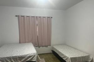 um quarto com 2 camas e uma janela com cortinas em CASA DE FÉRIAS II em Barra do Garças