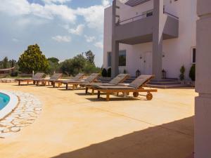 a row of lounge chairs next to a building at Grey Haven Luxury Villa in Stérnai