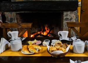 a table with croissants and pastries in front of a fireplace at Hotel San Marcos in San Marcos Sierras