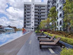 a swimming pool with benches next to a building at Armadale Residence @Gala City 3 bedroom in Kuching