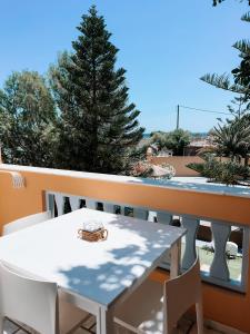 een witte tafel en stoelen op een balkon met een boom bij Joy Beach Ηotel in Perivolos