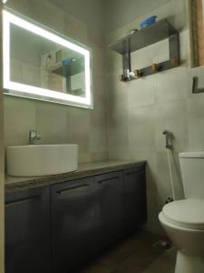 een badkamer met een wastafel, een toilet en een spiegel bij A Goan Nest in Marmagao