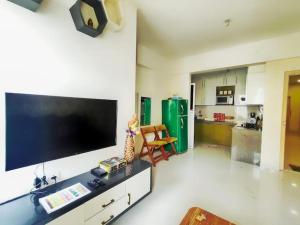 een woonkamer met een grote flatscreen-tv aan de muur bij A Goan Nest in Marmagao
