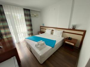 Finike Marina Hotel في فينيقيه: غرفة نوم عليها سرير وفوط